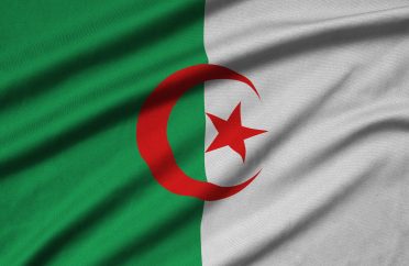 Algeria flag is depicted on a sports cloth fabric with many folds. Sport team waving banner