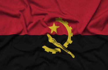 Angola flag is depicted on a sports cloth fabric with many folds. Sport team waving banner