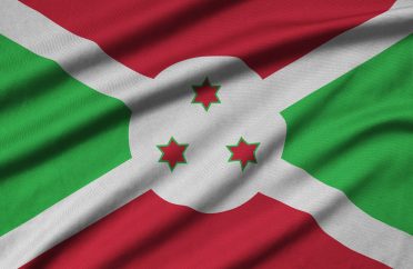 Burundi flag is depicted on a sports cloth fabric with many folds. Sport team waving banner