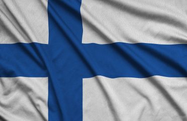 Finland flag is depicted on a sports cloth fabric with many folds. Sport team waving banner