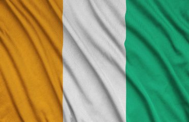 Ivory Coast flag is depicted on a sports cloth fabric with many folds. Sport team waving banner