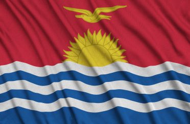 Kiribati flag is depicted on a sports cloth fabric with many folds. Sport team waving banner