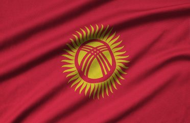 Kyrgyzstan flag is depicted on a sports cloth fabric with many folds. Sport team waving banner