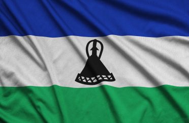 Lesotho flag is depicted on a sports cloth fabric with many folds. Sport team waving banner