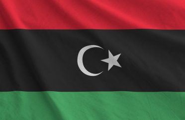 Libya flag depicted on folded wavy fabric of old cloth