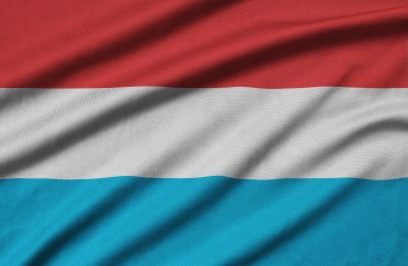 Luxembourg flag is depicted on a sports cloth fabric with many folds. Sport team waving banner