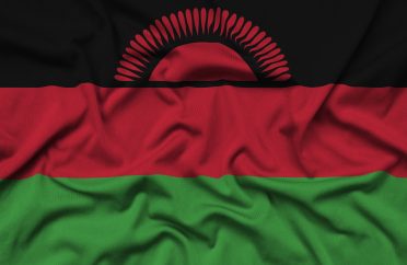 Malawi flag is depicted on a sports cloth fabric with many folds. Sport team waving banner