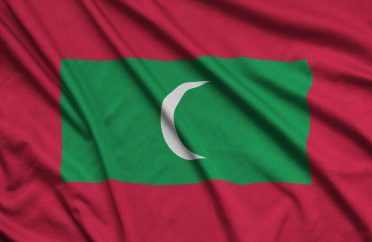 Maldives flag is depicted on a sports cloth fabric with many folds. Sport team waving banner