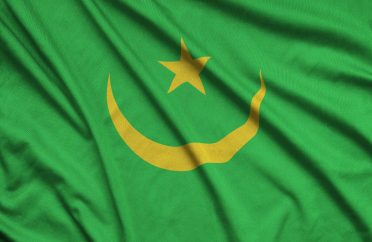 Mauritania flag is depicted on a sports cloth fabric with many folds. Sport team waving banner