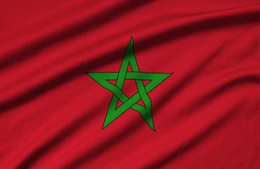 Morocco flag is depicted on a sports cloth fabric with many folds. Sport team waving banner