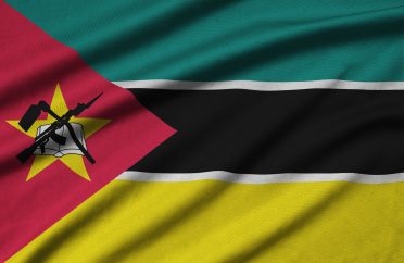 Mozambique flag is depicted on a sports cloth fabric with many folds. Sport team waving banner