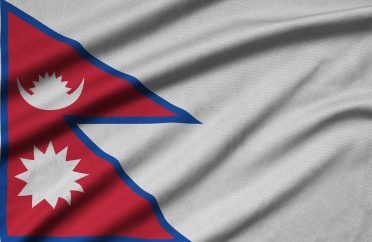 Nepal flag is depicted on a sports cloth fabric with many folds. Sport team waving banner