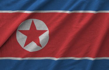 North Korea flag depicted on folded wavy fabric of old cloth