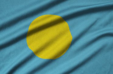 Palau flag is depicted on a sports cloth fabric with many folds. Sport team waving banner