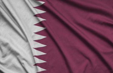 Qatar flag is depicted on a sports cloth fabric with many folds. Sport team waving banner