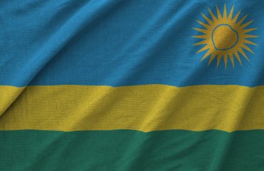 Rwanda flag depicted on folded wavy fabric of old cloth