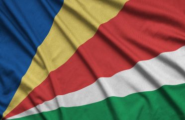 Seychelles flag is depicted on a sports cloth fabric with many folds. Sport team waving banner