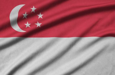 Singapore flag is depicted on a sports cloth fabric with many folds. Sport team waving banner