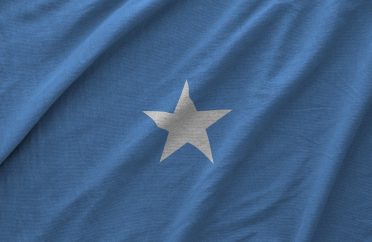 Somalia flag depicted on folded wavy fabric of old cloth