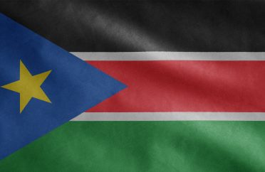 Sudanese flag waving in the wind. Close up South Sudan banner blowing soft silk.