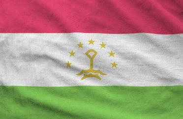 Tajikistan flag depicted on folded wavy fabric of old cloth