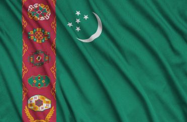 Turkmenistan flag is depicted on a sports cloth fabric with many folds. Sport team waving banner