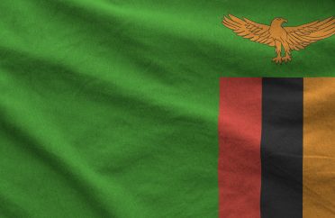 Zambia flag depicted on folded wavy fabric of old cloth