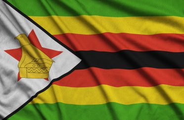 Zimbabwe flag is depicted on a sports cloth fabric with many folds. Sport team waving banner